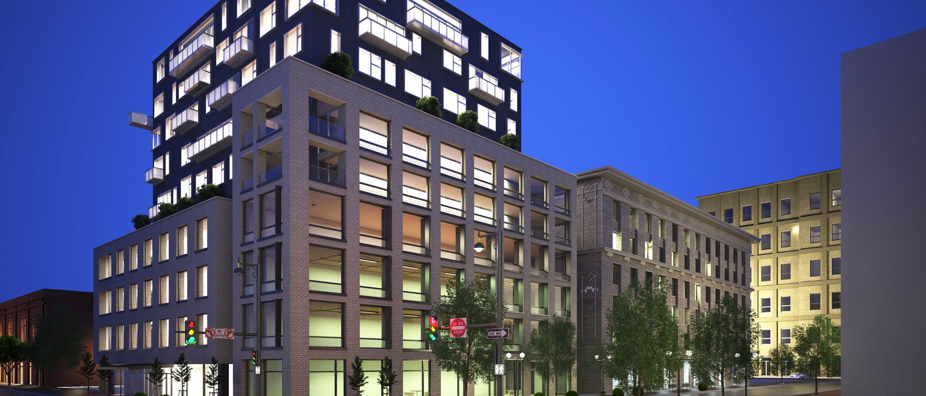 Mixed-use building at dusk with residential floors above a lit retail podium